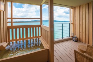 Terraza de madera con un jacuzzi y vista al mar.