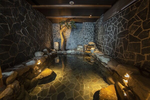 A spa area with a stone wall, a small waterfall, and a tree. - Shirasaginoyu notokaisyu (Nanao)