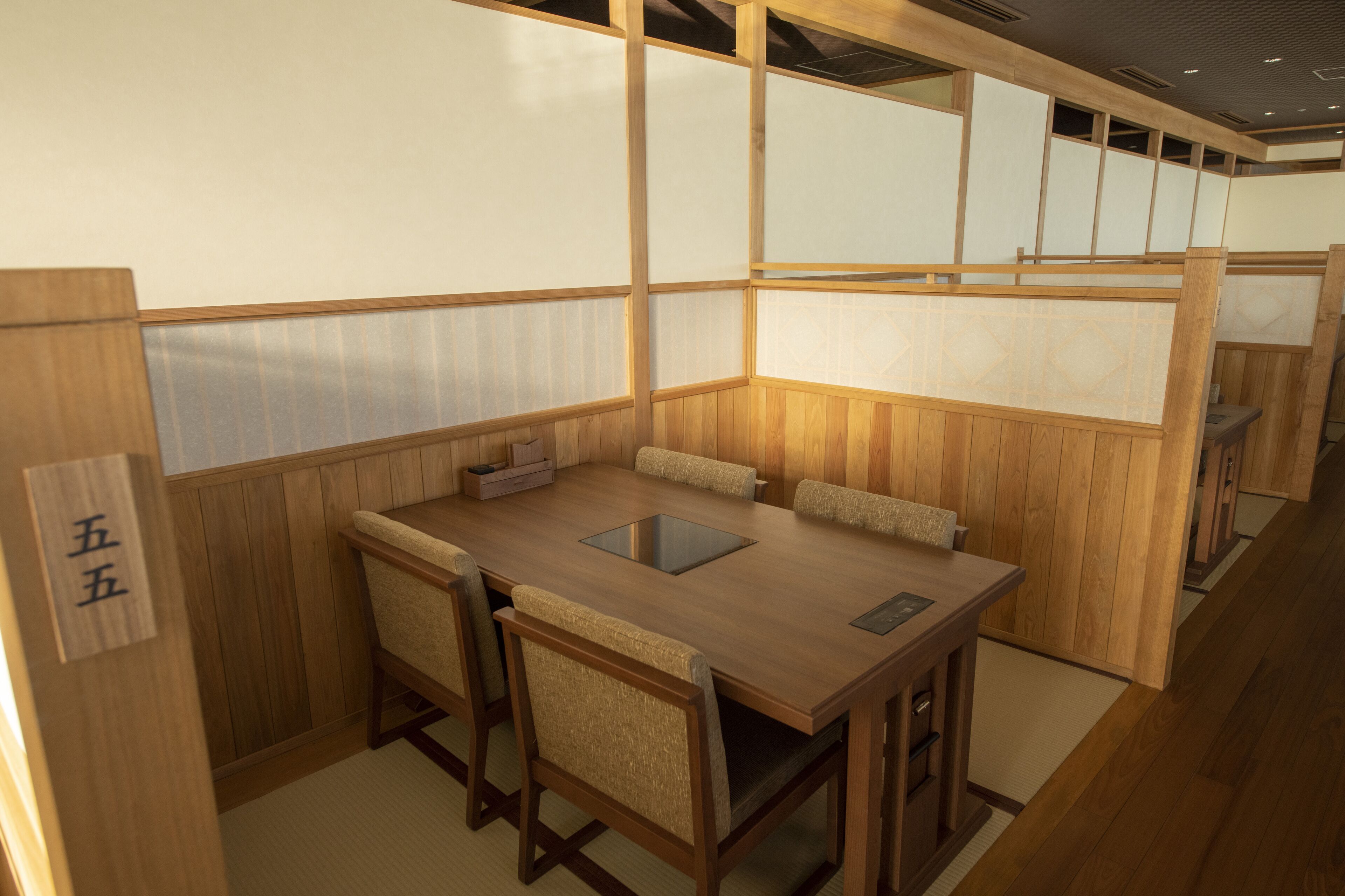 Una habitación tradicional japonesa con suelo de tatami, una mesa de madera con cojines y puertas correderas shoji.