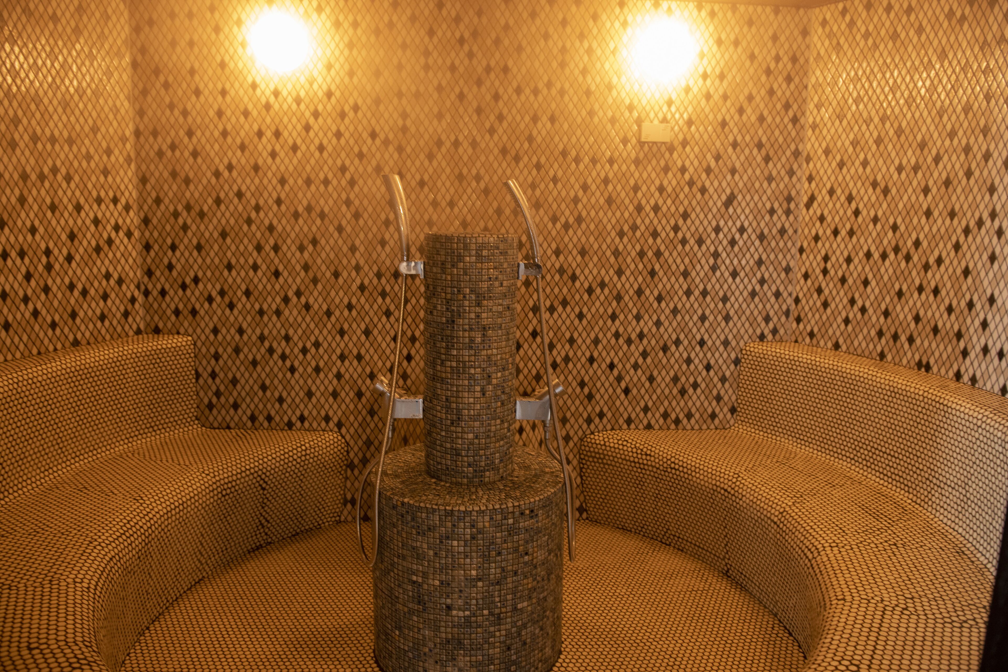 A room with a circular seating area, a central pillar, and a patterned wall.