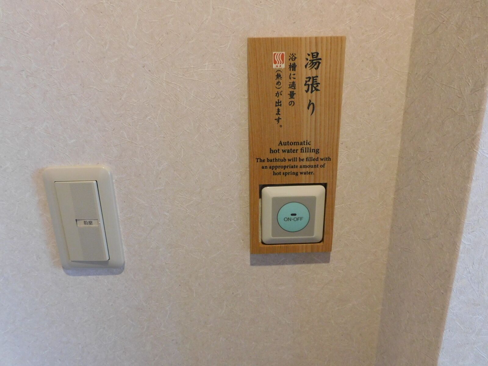 A wall-mounted control panel with Japanese text and an automatic hot water filling feature.