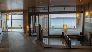 Un hall d’hôtel moderne avec vue sur la mer, un sol carrelé en pierre et une esthétique d’inspiration japonaise traditionnelle.