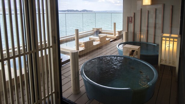 Un espace avec un bain à remous offrant une vue sur la mer, une terrasse en bois et une lanterne.