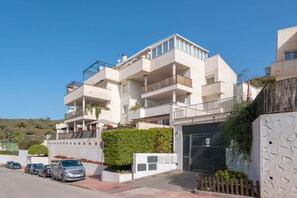 A multi-story residential building with balconies, a gated entrance, and parked cars. - Renthas Cumbres de Golf (Rincon De La Victoria)