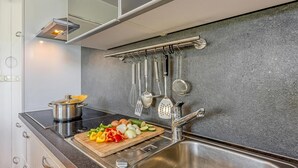 A modern kitchen with a stainless steel sink, a cutting board with vegetables, and various kitchen utensils hanging on the wall. - Sea Breeze Residence Mariella, Umag, Croatia (Umag)