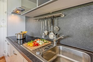 Una cucina moderna con un lavello in acciaio inossidabile, un tagliere con verdure e diversi utensili da cucina appesi al muro.