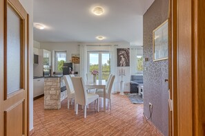 Un vaste espace de vie comprenant un coin repas avec table et chaises, un espace cuisine et un balcon offrant une vue agréable.