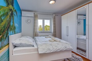 Une chambre à coucher avec un lit, des rideaux, une fenêtre, une armoire et une fresque murale.