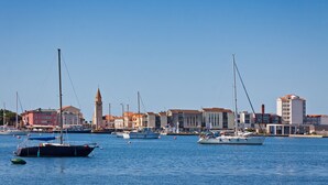 A marina with boats, a clock tower, and buildings with red roofs. - Sea Breeze Residence Mariella, Umag, Croatia (Umag)
