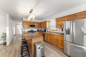 A modern kitchen with wooden cabinets, stainless steel appliances, and a central island with stools.