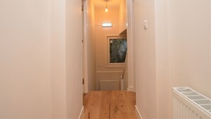 A narrow hallway with a wooden floor, a ceiling light, and a window with a view of trees. - Pedals and Paddles, waterfront (Dunoon)