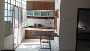 Una cocina compacta con armarios de madera, una mesa pequeña y una ventana con persianas.