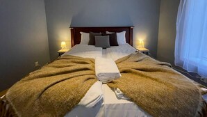 A neatly made bed with a brown blanket, white linens, and a folded towel in the center. There are two bedside lamps on either side of the bed. - Charming 2-Bed Apartment in Stavanger (Stavanger)