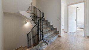 A modern staircase with a black metal railing, leading to a room with a wooden floor and a white door. - Villa Monica - Iglesias (Iglesias)