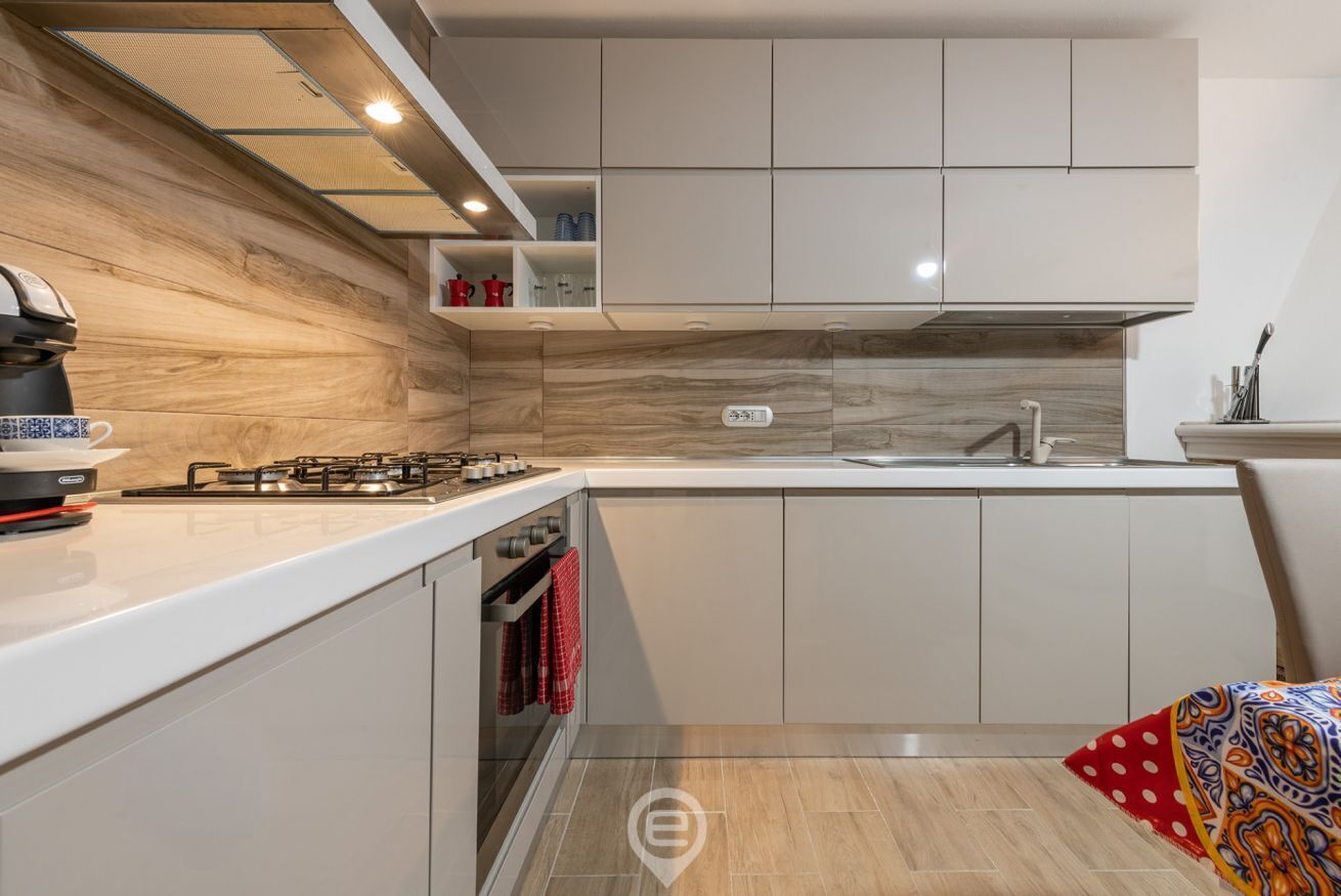 Eine moderne Küche mit weißen Schränken, einem Gasherd und einem eingebauten Backofen.