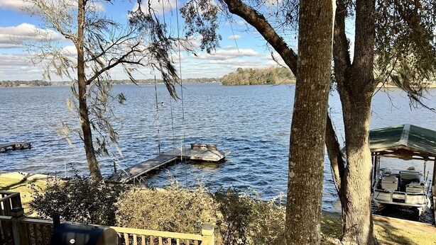 Um deck à beira do lago com churrasqueira, um cais e um barco.