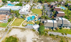 An aerial view of Fripp Island Beach Club with multiple buildings, a large pool area, and a beach.