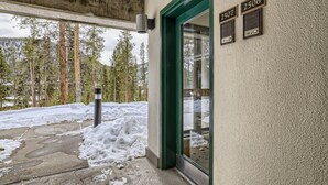 A building entrance with a green door, numbered plaques, and a snow-covered ground. - Views Overlooking Keystone w/ Shuttle to Lifts (Keystone)