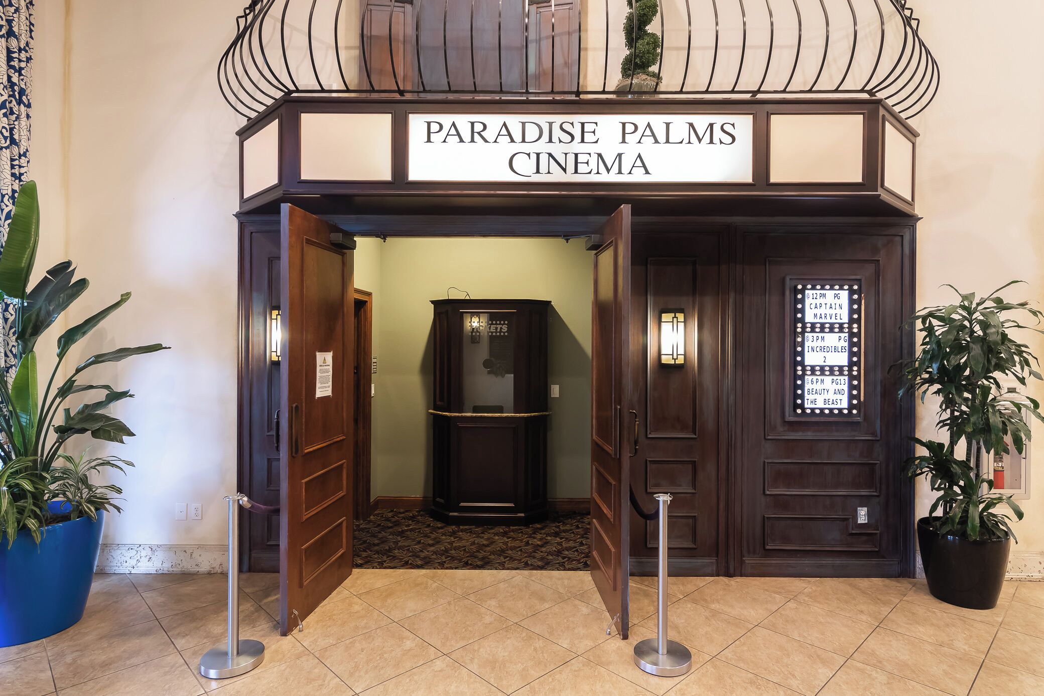 L’entrée du cinéma Paradise Palms, avec une enseigne au-dessus des portes et un guichet à l’intérieur.