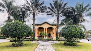 A building with a central entrance, flanked by palm trees and surrounded by well-maintained lawns and shrubs. - Main Street in Paradise Palms (Kissimmee)