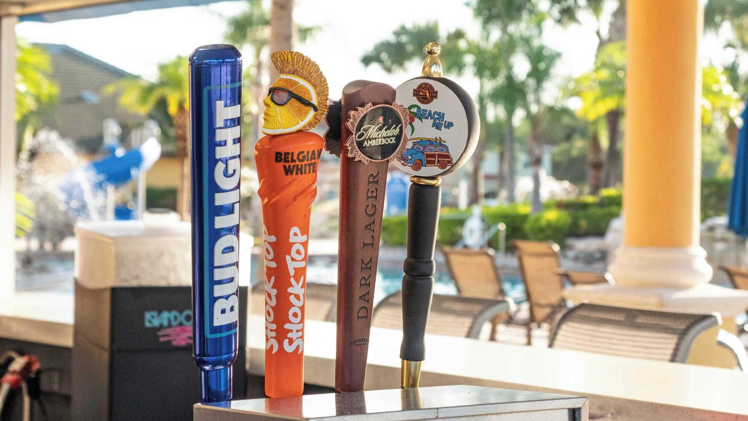 A row of beer taps with labels including Bud Light, Belgian White, Shock Top, Dark Lager, and Beach Me Up.