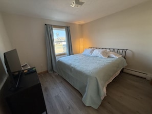 Ein Schlafzimmer mit einem Bett, einem Schreibtisch und einem Fenster mit Vorhängen.