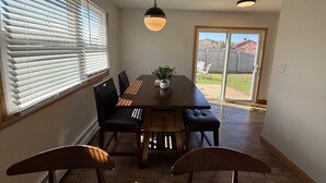 Een eetgedeelte met een houten tafel, zwarte stoelen en een hangende lamp.