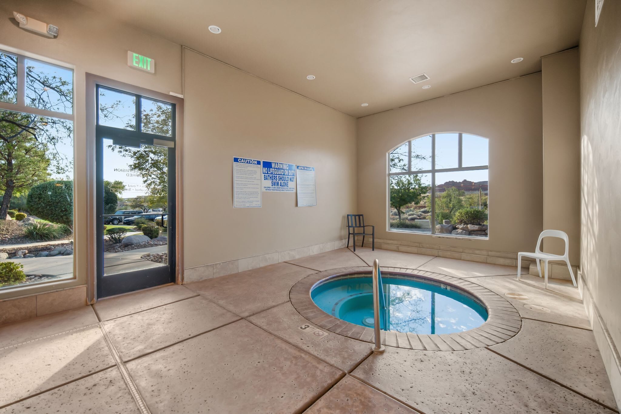 Una piscina interior con vistas despejadas al exterior, una silla junto a la piscina y un cartel en la pared.