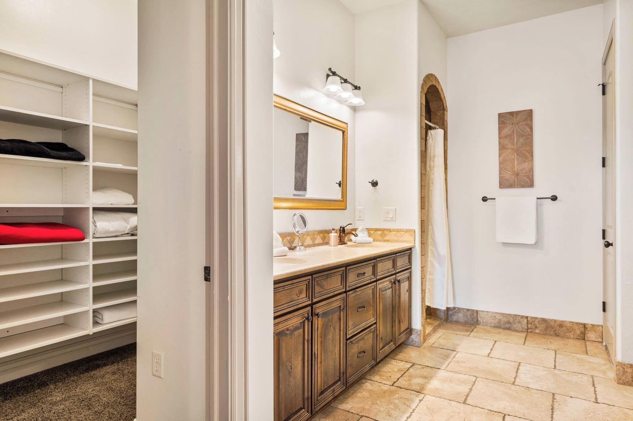 A bathroom with a vanity, a mirror, a towel rack, and a shower area.