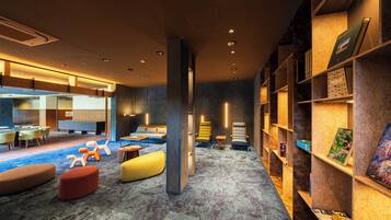 A modern lounge area with seating, a coffee table, and a bookshelf with books and a framed picture.