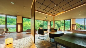 Ein geräumiges Zimmer mit großen Fenstern, Holzboden und einem grünen Sofa.