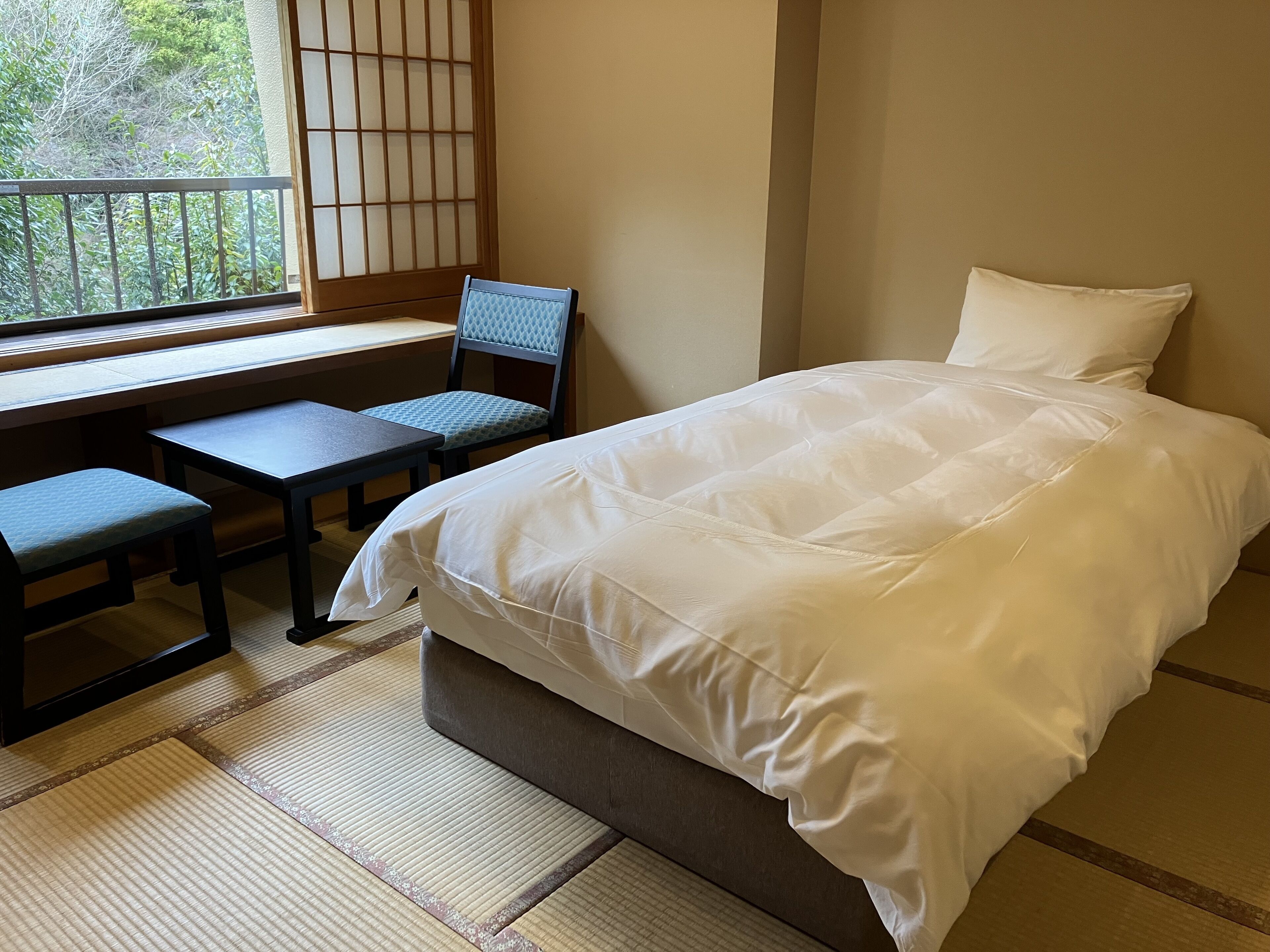 Een slaapkamer met een bed, een bureau en een stoel.