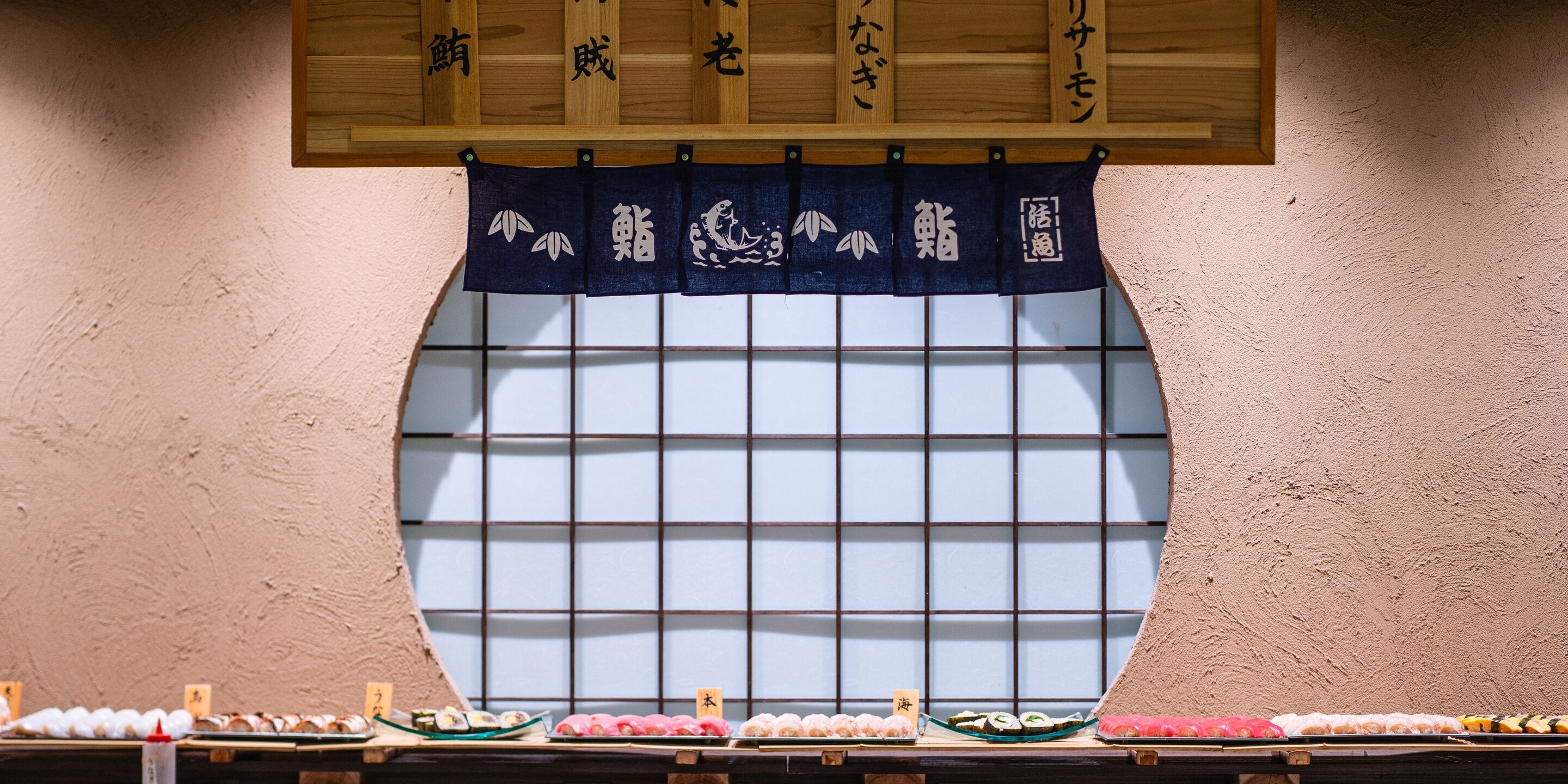 Un bar de sushi con una ventana tradicional japonesa y señalización de madera.
