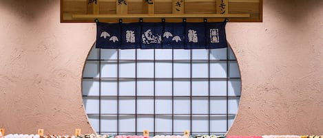 Un bar de sushi con una ventana tradicional japonesa y señalización de madera.