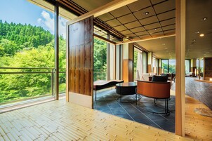 Una habitación amplia con ventanas grandes, suelo de madera y un área de descanso con una mesa redonda y sillas.