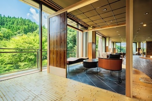 A spacious room with large windows, a wooden floor, and a seating area with a round table and chairs.