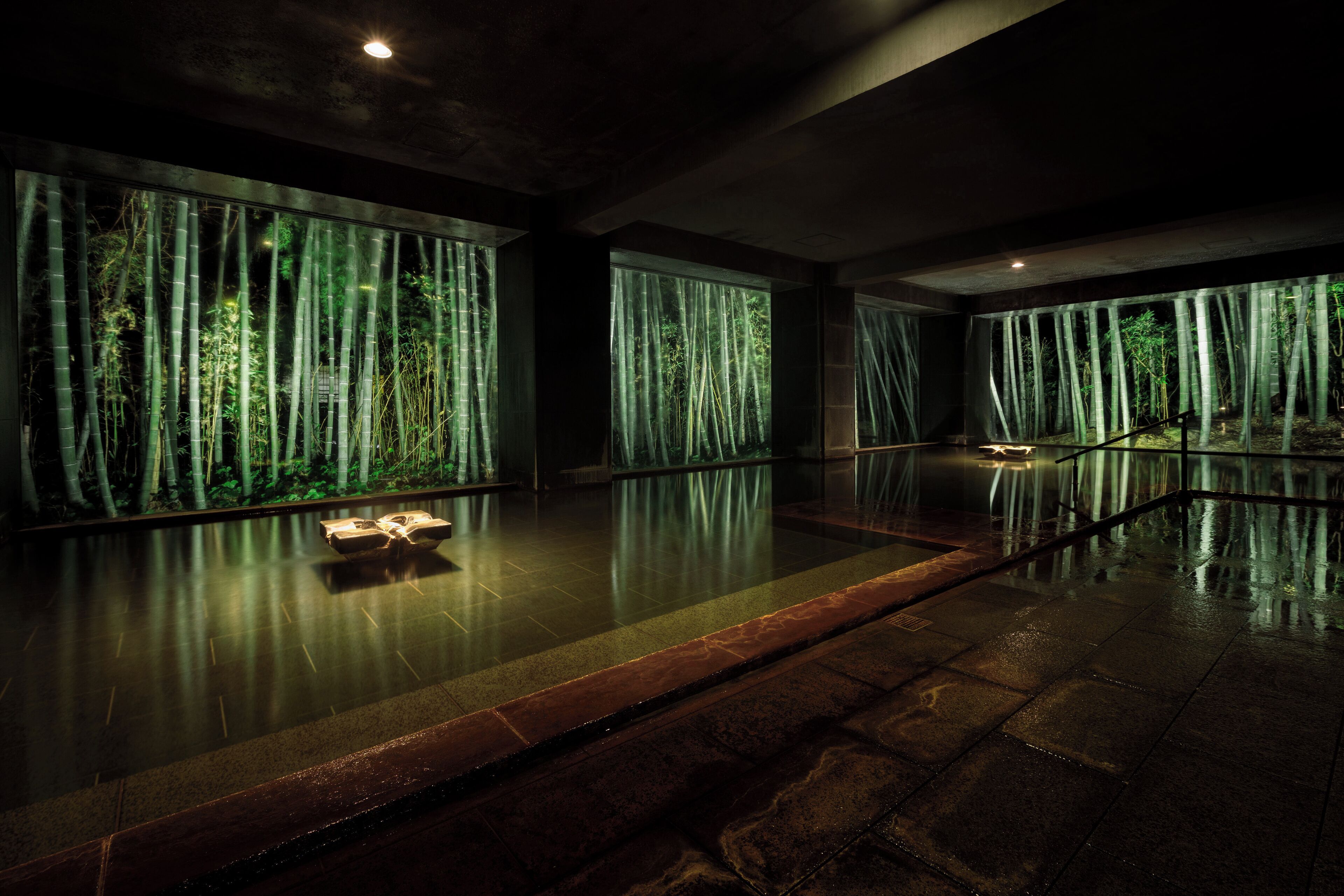 Un amplio espacio interior con ventanas grandes que ofrecen vistas a un bosque de bambú.
