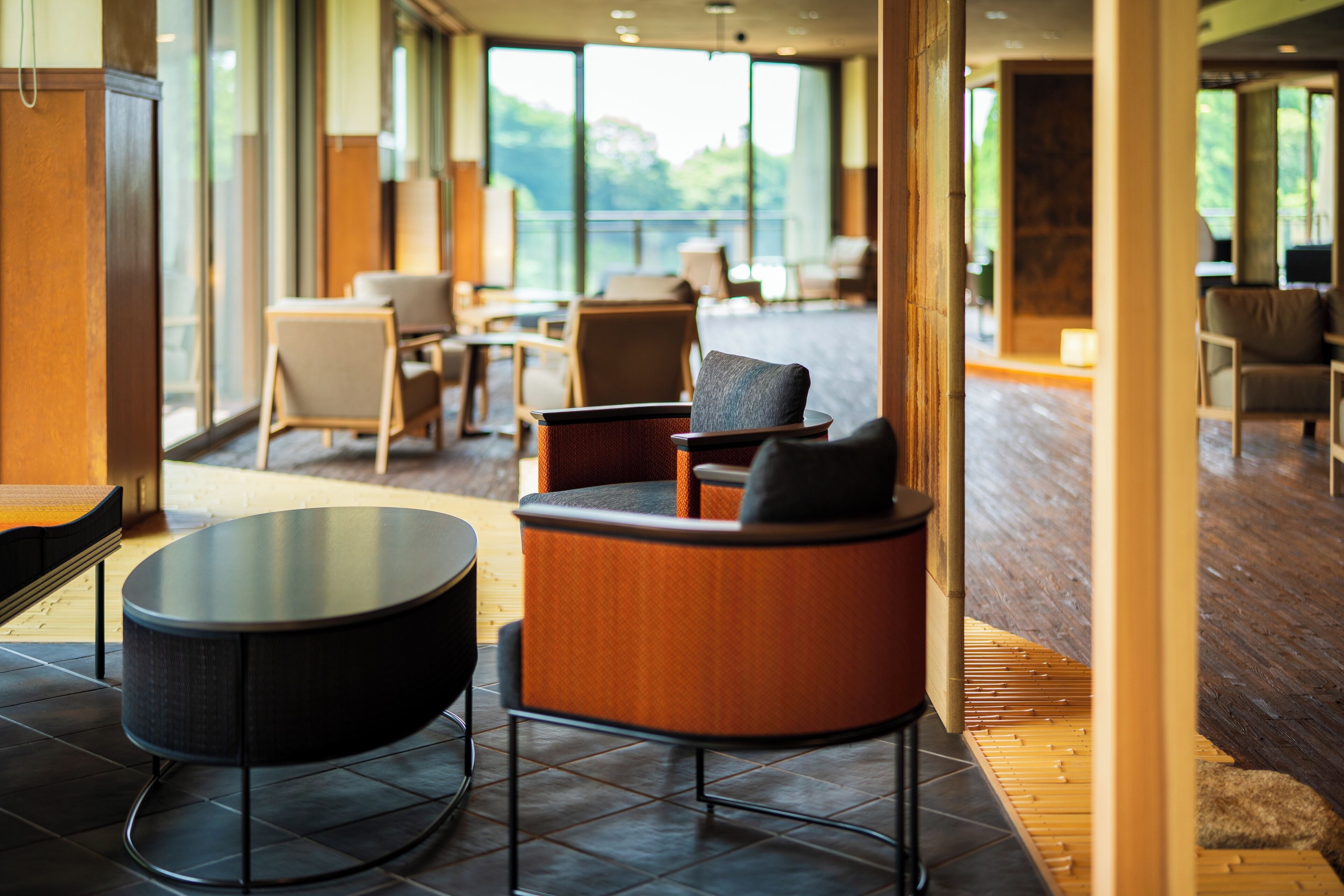 Un vestíbulo de hotel moderno con una mesa redonda, asientos cómodos y grandes ventanales con vistas al exterior.