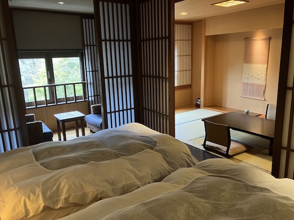 Une pièce de style japonais traditionnel, avec un sol recouvert de tatamis, une table basse et un lit doté de grands oreillers.