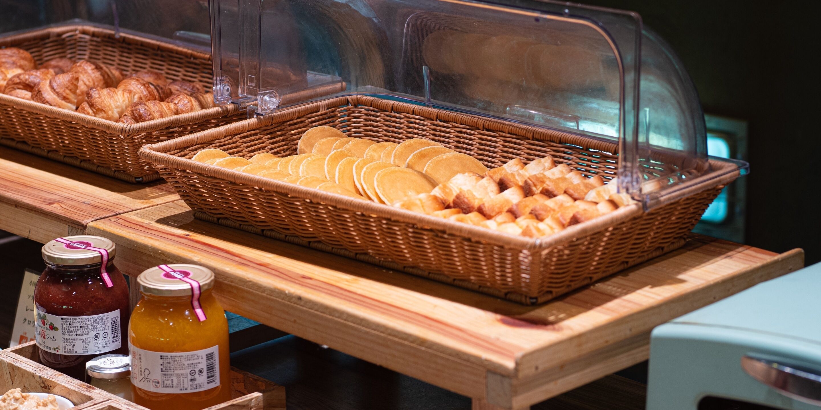 A bakery display with croissants and pastries, and two jars of jam.