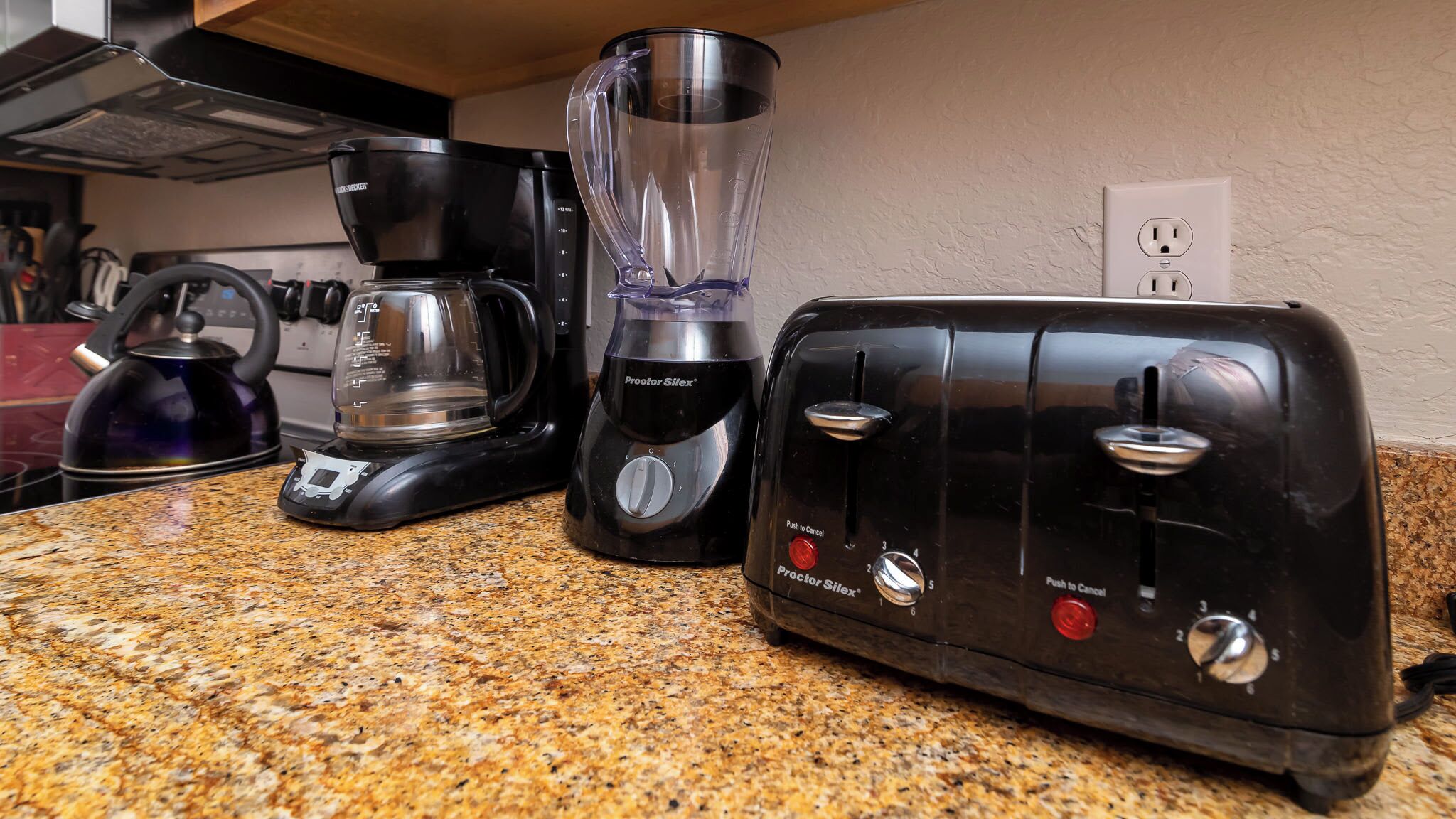 A kitchen counter with a coffee maker, a blender, and a toaster.
