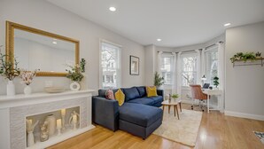 A modern living room with a sectional sofa, fireplace, and a large mirror. - Palmer Square 1BR w/ Private Patio (Princeton)