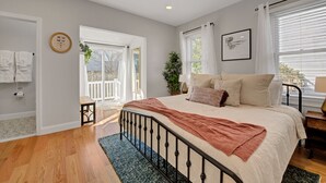 A bedroom with a large bed, a window with blinds, a plant, and a view of the outside. - Palmer Square 1BR w/ Private Patio (Princeton)