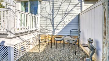 A patio with two metal chairs, a small round table, and a decorative frog statue.