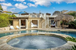Un resort con piscina, mobiliario exterior y una estructura con techo de paja.