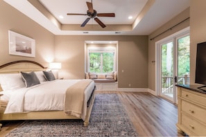 A bedroom with a bed, a ceiling fan, a window, and a view of the outdoors.