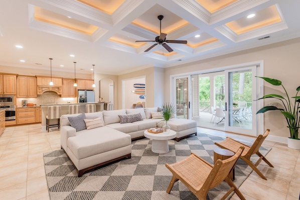 A spacious living area with a large sofa, a coffee table, and a dining area with chairs.