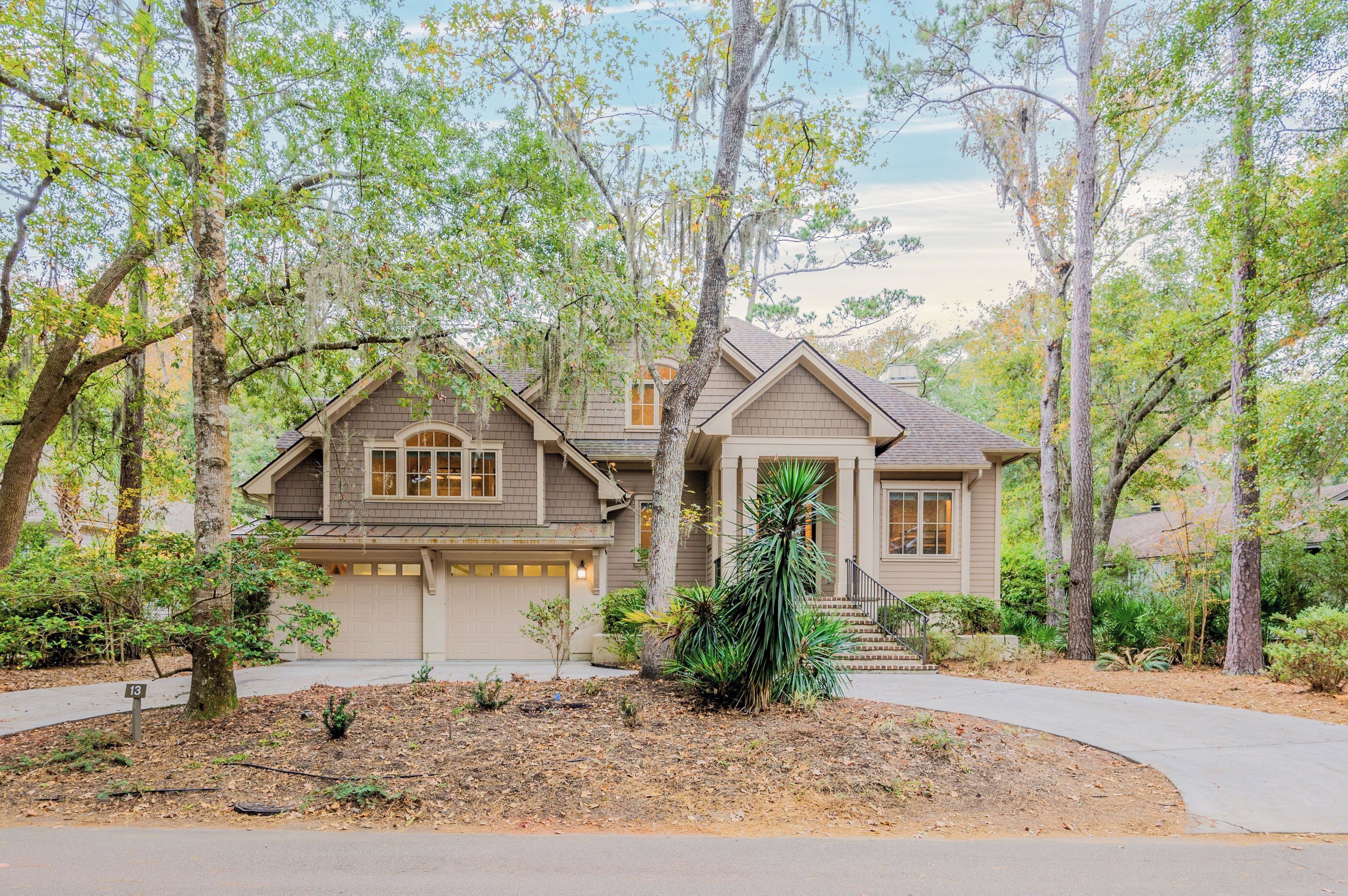 A two-story house with a garage, surrounded by trees and a landscaped yard.