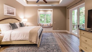 Quarto com cama, ventilador de teto, janela e vista para o exterior.