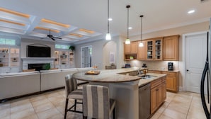 Cozinha moderna com ilha central, banquetas, armários de madeira e iluminação pendente.